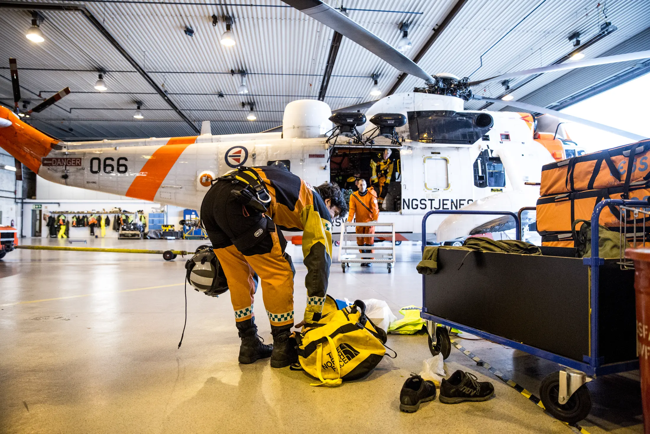 Redningsmannskap klargjør utstyr ved et Sea King-helikopter, med LESS bårepakker på trallen ved siden av.